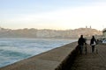 San Sebastian / Spain - January 10, 2015: A young man and woman are rolling bicycles along the evening promenade of the city of Sa Royalty Free Stock Photo