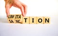 Sanction and limitation symbol. Businessman turns cubes, changes the word limitation to sanction. Beautiful white table, white