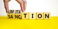 Sanction and limitation symbol. Businessman turns cubes, changes the word limitation to sanction. Beautiful yellow table, white