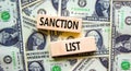 Sanction list symbol. Wooden blocks with concept words Sanction list on beautiful background from dollar bills. Business political