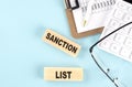 SANCTION LIST word concept on a magnifier on the keyboard