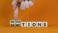 Sanctions or limitations symbol. Businessman turns cubes, changes the word sanctions to limitations. Beautiful orange table,