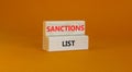 Sanctions list symbol. Wooden blocks with concept words Sanctions list on beautiful orange background. Business political