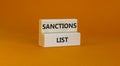 Sanctions list symbol. Wooden blocks with concept words Sanctions list on beautiful orange background. Business political