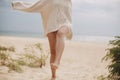 Sand on background of beautiful woman legs barefoot walking on sandy beach and having fun, close up. Carefree vacation mood.