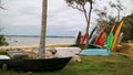 A sand beach atmosphere with colorful kayaks, canoes, a boat and trees. Royalty Free Stock Photo