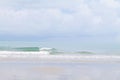 Sand beach and clear transparent sea wave with foam and blue sky