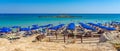 Sand beach with crystal clear waters of Fig Tree Bay with a small island on the horizon and numerous water activities