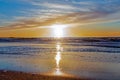 Sand beach with endless horizon and foamy waves under the bright sundown with yellow colors and clouds above the sea Royalty Free Stock Photo