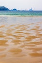 Sand beach in low tide with a lighthouse at sea Royalty Free Stock Photo
