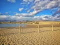 Sand on the beach with a metal fence by the blue sea on a sunny day Royalty Free Stock Photo