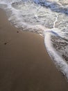 sand beach and sea waves top view. Soft wave and sunny sand shore. Vertical photo.