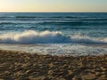 Sand beach with splashing waves at sunset Royalty Free Stock Photo