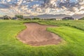 Sand bunker and green fairway of a golf course with blue sky and clouds overhead Royalty Free Stock Photo