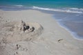 Sand castle on the beach. Fragile sand house near the sea wave Royalty Free Stock Photo