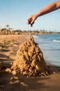 Sand castle made of sand by the hands of a child on the shore.Sea at sunset, white sand on the beach.Sunset sun, yellow