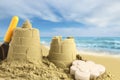 Sand castles with toys on ocean beach, closeup. Outdoor play Royalty Free Stock Photo
