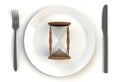 Sand clock on plate, knife and fork on white table