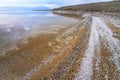 Sand covered with crystalline salt on shore of Dead Sea, calm clear water near - typical scenery at Ein Bokek beach Royalty Free Stock Photo