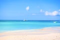 The sand and the crystal sea water of the Saona island, with some boats carrying tourists on the horizon.