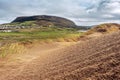 Sand dune, green grass field and Strandhill town and Knocknarea hill in the background. Cloudy sky, County Sligo, Ireland Royalty Free Stock Photo