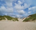 Sand dunes of the beach Nymindegab Strand in Denmark under vivid blue sky and white clouds Royalty Free Stock Photo