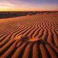 Sand dunes with rippled patterns under a sunset sky create a Royalty Free Stock Photo