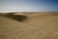 Sand dunes with walking people and ocean behind