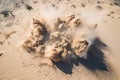 sand explosion seen from above, with sand and debris flying in every direction