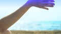 Sand flows through fingers against the background of the sea and sky