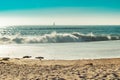 Sand and foam of powerful waves crashing on Figueira da Foz beach with fog and sailing boat on the horizon, PORTUGAL Royalty Free Stock Photo