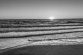 Black and white photo of sand ocean and sun at sunset Royalty Free Stock Photo