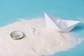 Sand with paper boat, compass and anchor Royalty Free Stock Photo