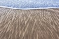 Sand patterns and wave on beach Royalty Free Stock Photo