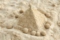 Sand pyramid on beach surrounded by spherical sand sculptures in sunlit setting Royalty Free Stock Photo