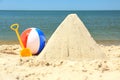 Sand pyramid, colorful ball and plastic shovel on beach