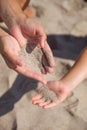Sand running through female hands into kid`s hands.Young woman with sand in her hands playing with a child Royalty Free Stock Photo