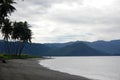 Sand sea coast with palms mountain view Royalty Free Stock Photo