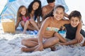 Sand and sea. A family of five sitting under their umbrella at the beach. Royalty Free Stock Photo