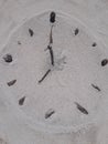 Sand and stick beach clock face 7 o clock Royalty Free Stock Photo