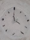 Sand and stick beach clock face 4 o clock Royalty Free Stock Photo