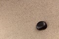 Black stone on sand top view vertical zen concept photo. Zen stone garden with meditation stone