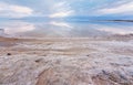 Sand and stones covered with crystalline salt on shore of Dead Sea, calm clear water near - typical scenery at Ein Bokek beach, Royalty Free Stock Photo