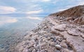 Sand and stones covered with crystalline salt on shore of Dead Sea, clear water near - typical scenery at Ein Bokek Royalty Free Stock Photo