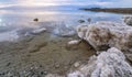 Sand and stones covered with crystalline salt on shore of Dead Sea, clear water near - typical scenery at Ein Bokek beach, Israel Royalty Free Stock Photo