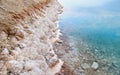 Sand and stones covered with crystalline salt on shore of Dead Sea, clear water near - typical scenery at Ein Bokek beach, Israel Royalty Free Stock Photo