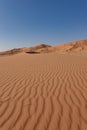 Sand streaks of the red Rub al Khali desert against a backdrop of dunes and blue sky. Royalty Free Stock Photo