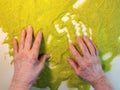 Sand therapy, hands of an elderly woman on green kinetic sand, the concept of rehabilitation of the elderly after a stroke