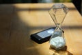 Sand watch glass with wireless pager on wood table in cafe with sun light from the window Royalty Free Stock Photo