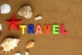 On the sand is written the word `Travel` in English in bright letters. Nearby are seashells and a red star. Royalty Free Stock Photo